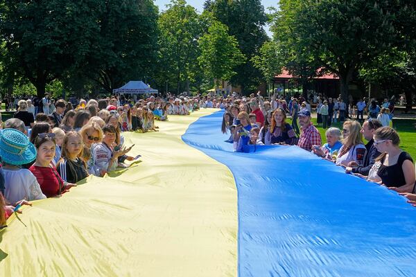 People from Ukraine hold a giant Ukrainian flag during a family meeting with their Eurovision band Ziferblat in a park in Basel as part of the 69th Eurovision Song Contest week, in Basel, Switzerland, Thursday, May 15, 2025. (AP Photo/Martin Meissner)
