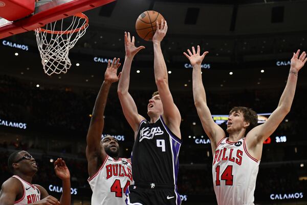 Sacramento Kings' Kevin Huerter (9) goes up to shoot against Chicago Bulls' Patrick Williams (44), Matas Buzelis (14) and Jevon Carter, left, during the first half of an NBA basketball game on Sunday, Jan. 12, 2025, in Chicago. (AP Photo/Paul Beaty)