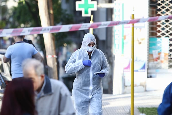 A Greek police forensic expert searches for evidence at the area where a 38-year-old woman was killed early Saturday when a bomb she was carrying exploded in her hands outside a bank branch, local police said, in Thessaloniki, northern Greece, May 3, 2025. (AP Photo/Giannis Papanikos)