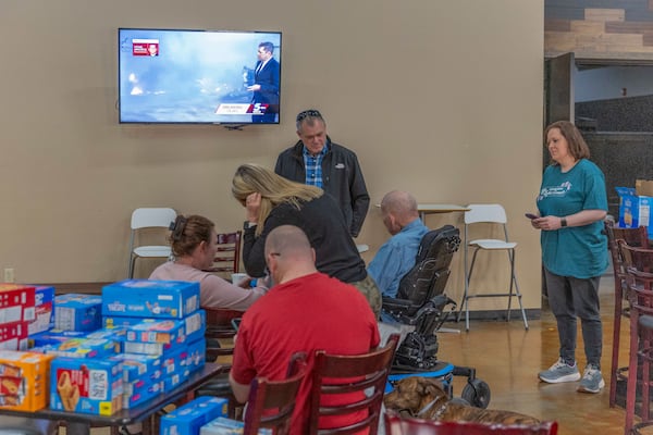 Families evacuated from wildfires near Norman, Okla. talk and watch the latest news information on tv at CrossPoint Church in Norman on Friday, March 14, 2025. (AP Photo/Alonzo Adams)