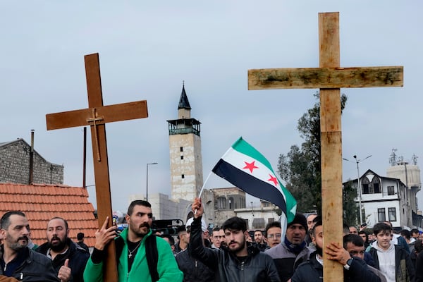 Syrian Christians carry crosses and shout slogans, as they march during a protest after a Christmas tree was set on fire in Hamah city on Sunday, in Damascus, Syria, Tuesday, Dec. 24, 2024.(AP Photo/Hussein Malla)