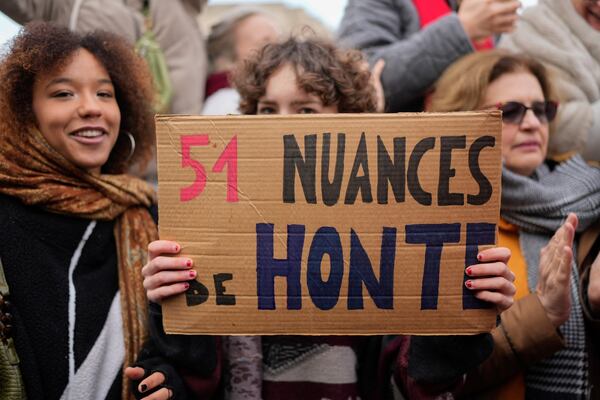 A woman holds a placard reading "51 shades of shame" outside the Avignon courthouse, southern France, Thursday, Dec. 19, 2024. (AP Photo/Lewis Joly)