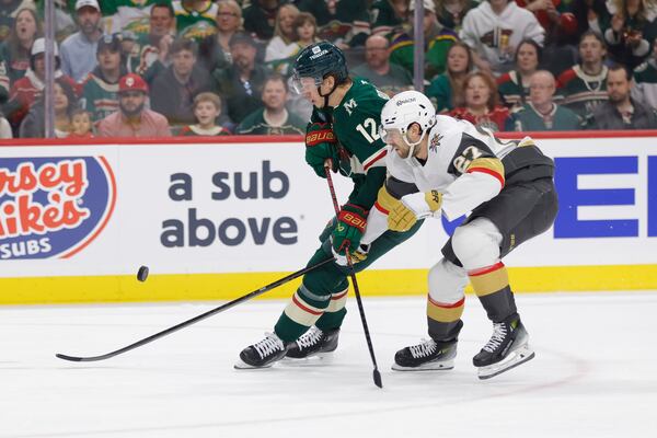 Minnesota Wild left wing Matt Boldy (12) and Vegas Golden Knights defenseman Shea Theodore (27) battle for the puck during the first period of Game 6 of a first-round NHL hockey playoff series Thursday, May 1, 2025, in St. Paul, Minn. (AP Photo/Bailey Hillesheim)