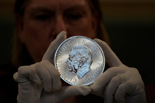 A warden inspects a 500 Pounds commemorative coin during the "Trial of the Pyx,'' a ceremony that dates to the 12th Century in which coins are weighed in order to make certain they are up to standard, at the Goldsmiths' Hall in London, Tuesday, Feb. 11, 2025.(AP Photo/Frank Augstein)