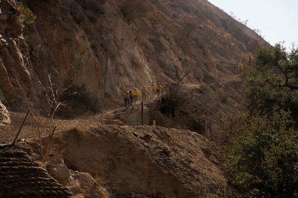 Members of Navajo Scouts firefighter crew hike up a road to clear debris from landslide across a road at the Eaton Fire, Friday, Jan. 17, 2025, in Altadena, Calif. (AP Photo/John Locher)