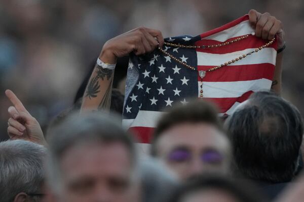 Faithful holds an American flag following the election of Pope Leo XIV at the Vatican, Thursday, May 8, 2025. (AP Photo/Andrew Medichini)