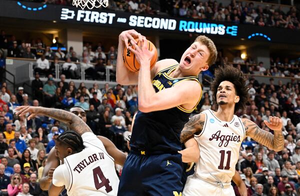 Michigan center Danny Wolf, center, pulls in a rebound as Texas A&M guard Wade Taylor IV, left, and forward Andersson Garcia, right, defend during the first half in the second round of the NCAA college basketball tournament Saturday, March 22, 2025, in Denver. (AP Photo/John Leyba)