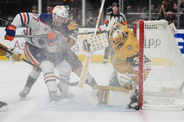 Vegas Golden Knights goaltender Adin Hill (33) stops the puck beside Edmonton Oilers center Connor McDavid (97) during the third period of Game 2 of a second-round NHL hockey playoff series Thursday, May 8, 2025, in Las Vegas. (AP Photo/John Locher)