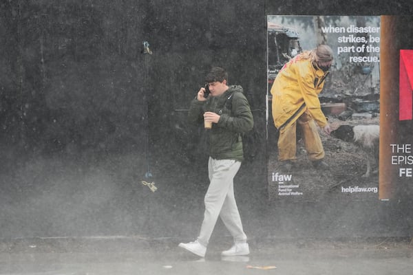 A pedestrian walks in the rain Thursday, Feb. 13, 2025, in Los Angeles. (AP Photo/Damian Dovarganes)