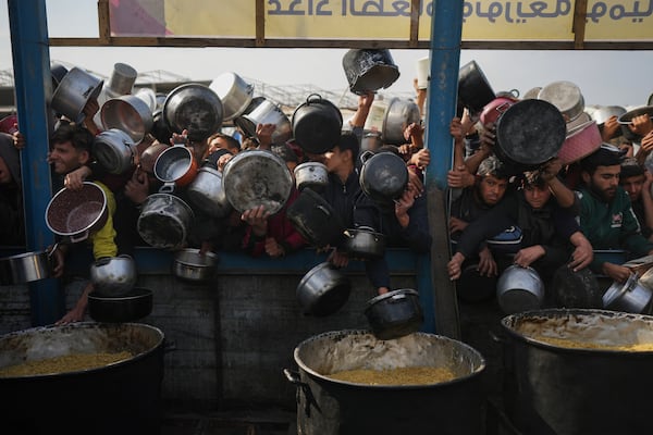 Palestinians struggle to reach for food at a distribution center in Khan Younis, Gaza Strip, Friday, Jan. 9, 2025. (AP Photo/Abdel Kareem Hana)