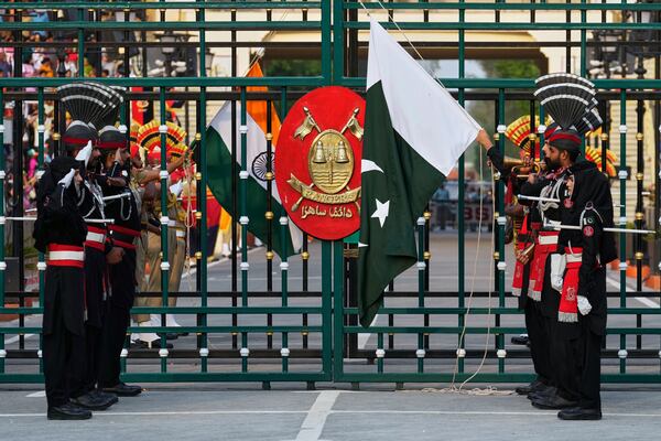 Pakistan's Rangers soldiers, in black, and Indian Border Security Forces soldiers, lower their flags during a daily closing ceremony at the Wagah, a joint post on the Pakistan and India border, near Lahore, Pakistan, Saturday, May 3, 2025. (AP Photo/K.M. Chaudary)