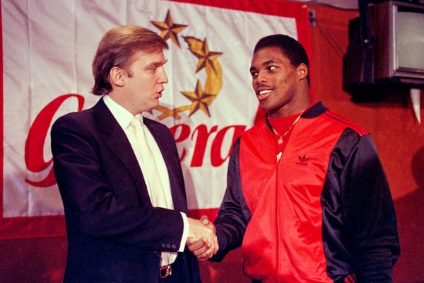 FILE - Donald Trump shakes hands with Herschel Walker in New York after agreement on a 4-year contract with the New Jersey Generals USFL football team, March 8, 1984. (AP Photo/Dave Pickoff, File)