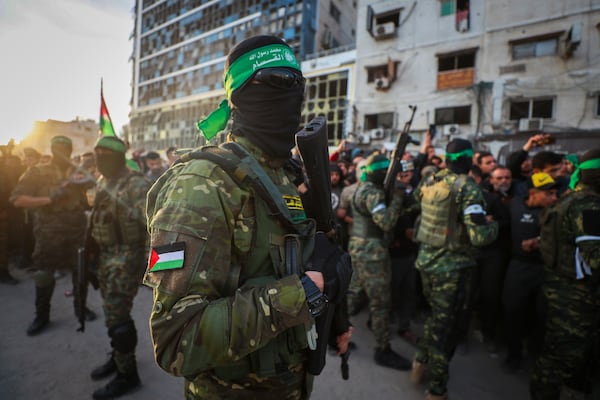 FILE - Fighters from the Qassam Brigades, the military wing of Hamas, control the crowd as Red Cross vehicles come to collect Israeli hostages under a ceasefire agreement between Israel and Hamas, in Gaza City, Jan. 19, 2025. (AP Photo/Abed Hajjar, File)