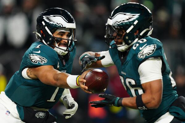 Philadelphia Eagles quarterback Jalen Hurts (1) hands the ball off to Philadelphia Eagles running back Saquon Barkley (26) during the first half of an NFL wild-card playoff football game against the Green Bay Packers on Sunday, Jan. 12, 2025, in Philadelphia. (AP Photo/Derik Hamilton)