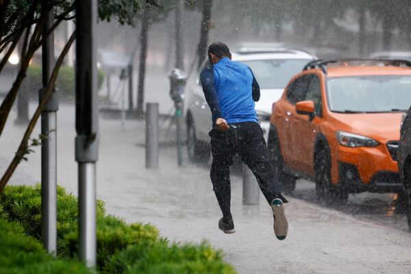 A man runs down the sidewalk along Commerce Street while heavy rain fall in downtown Dallas, Wednesday, April 30, 2025, and a flash flood warning was issued for parts of North Texas through this afternoon. (Elías Valverde II/The Dallas Morning News via AP)