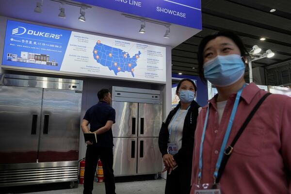 FILE - Visitors past by a map of the United States offices for Dukers, a manufacturer of refrigeration and cooking equipment, at the 137th Canton Fair, in Guangzhou in southern China's Guangdong province on April 15, 2025. (AP Photo/Ng Han Guan, File)