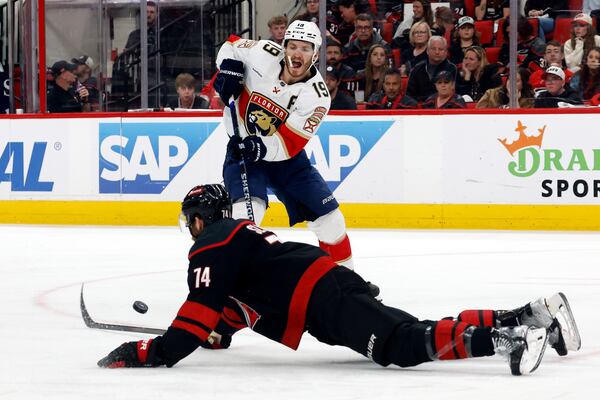 Florida Panthers' Matthew Tkachuk (19) passes the puck around a sliding Carolina Hurricanes' Jaccob Slavin (74) during the third period of Game 2 of the NHL hockey Stanley Cup Eastern Conference finals in Raleigh, N.C., Thursday, May 22, 2025. (AP Photo/Karl DeBlaker)