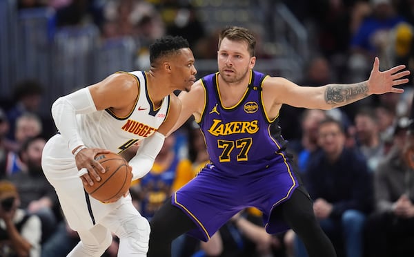 Denver Nuggets guard Russell Westbrook, left, looks to pass the ball as Los Angeles Lakers guard Luka Doncic defends in the first half of an NBA basketball game Saturday, Feb. 22, 2025, in Denver. (AP Photo/David Zalubowski)