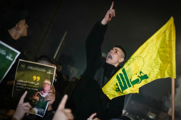 A Palestinian shouts next to a Hezbollah flag as a crowd waits for the arrival of the released Palestinian prisoners in the West Bank city of Beitunia, Sunday, Jan. 19, 2025. (AP Photo/Leo Correa)