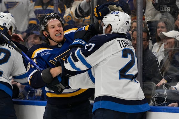 St. Louis Blues left wing Jake Neighbours, second from right, gets physical with Winnipeg Jets center Dominic Toninato, right, during the third period in Game 6 of an NHL hockey first-round playoff series Friday, May 2, 2025, in St. Louis. (AP Photo/Jeff Le)