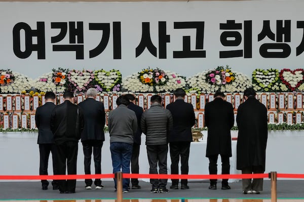 Mourners pray for the victims of a plane fire at a memorial altar at Muan sport park in Muan, South Korea, Monday, Dec. 30, 2024. The sign reads "The victims on a plane." (AP Photo/Ahn Young-joon)