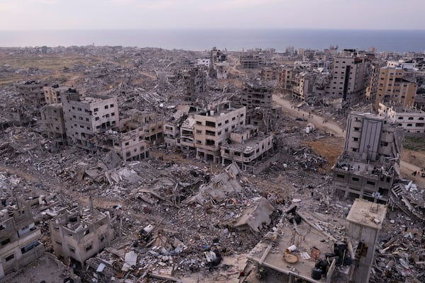 Palestinians walk through buildings that were destroyed by the Israeli air and ground offensive are seen at the Tel al-Hawa neighbourhood in Gaza Strip, Tuesday, Jan. 28, 2025. (AP Photo/Mohamamd Abu Samra)