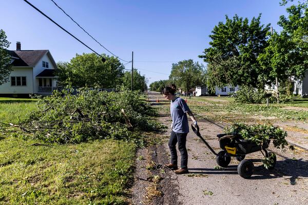 Zeeland resident Maddie Pellegrini clears debris outside her family's home on 64th Avenue in Drenthe east of Zeeland, Mich. on Friday, May 16, 2025. (Isaac Ritchey/The Grand Rapids Press via AP)