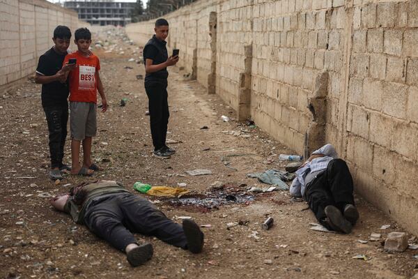 EDS NOTE: GRAPHIC CONTENT - Syrian boys take pictures with their mobile phones of the bodies of former Shanaya's town mayor Houssam Warawar and his son Haidar, who were killed in the town of Sahnaya, south of Damascus, Syria, Thursday, May 1, 2025, a day after clashes erupted between members of the minority Druze sect and pro-government fighters. (AP Photo/Ghaith Alsayed)