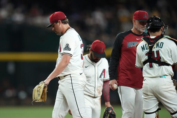 Arizona Diamondbacks pitcher Kevin Ginkel, left, walks off the field after being taking out by Diamondbacks manager Torey Lovullo, second from right, as catcher Gabriel Moreno, right, and third baseman Eugenio Suárez pause near the pitcher's mound during the eighth inning of a baseball game against the Pittsburgh Pirates Tuesday, May 27, 2025, in Phoenix. (AP Photo/Ross D. Franklin)