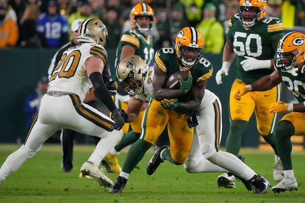 Green Bay Packers running back Josh Jacobs (8) carries against New Orleans Saints linebacker Pete Werner (20) during the first half of an NFL football game, Monday, Dec. 23, 2024, in Green Bay, Wis. (AP Photo/Morry Gash)