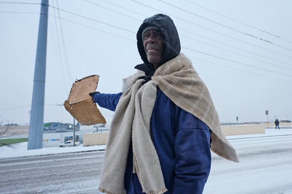 Frank Burnett, originally of Mississippi, uses a blanket to keep warm as he stands hoping for donations from passing motorists Thursday, Jan. 9, 2025, in Plano, Texas. (AP Photo/LM Otero)