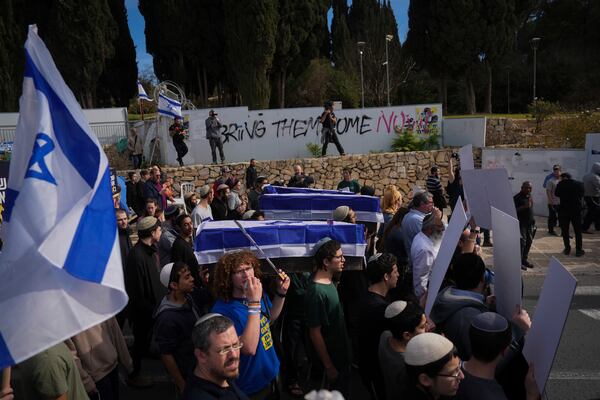 Activists representing families of Israelis killed during the war in Gaza carry mock coffins covered with Israeli flags that are meant to symbolize the price Israel will pay for agreeing to a ceasefire with Hamas in a demonstration against the deal , in Jerusalem on Thursday, Jan. 16, 2025. (AP Photo/Ohad Zwigenberg)