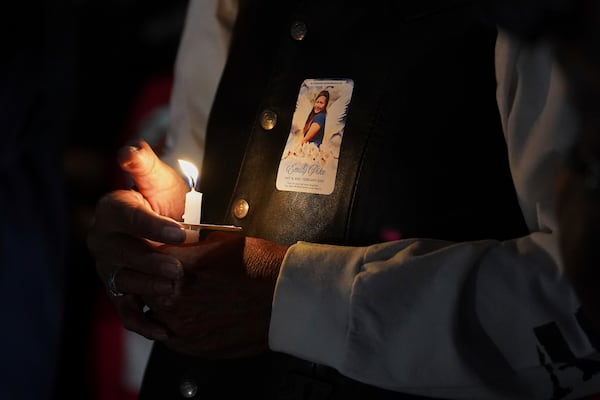 A holds a candle at a vigil for slain Native American teen Emily Pike, while wearing a sticker in her memory, in Mesa, Ariz., Thursday, March 6, 2025. (AP Photo/Samantha Chow)