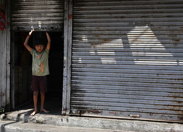 A boy looks out from the closed shutter of a shop a day after communal clashes sparked by protests demanding removal of the tomb of 17th-century Muslim Mughal ruler Aurangzeb in Nagpur, India, Tuesday, March 18, 2025. (AP Photo)