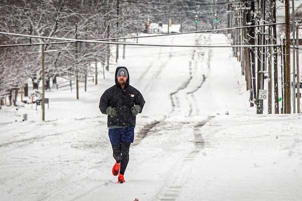 A jogger doesn't let the snowy weather stop his workout near South Pine and South Court Street, Friday, Jan. 10, 2025, in Florence, Ala. (Dan Busey/The TimesDaily via AP)