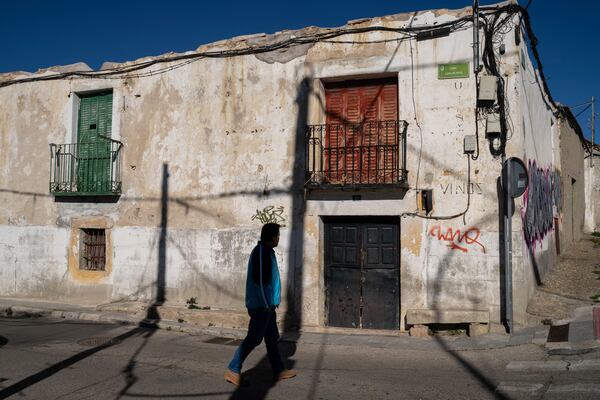 A man walks past an abandoned house in the village of La Cabrera, on the outskirts of Madrid, Spain, Tuesday, Jan. 14, 2025. (AP Photo/Bernat Armangue)