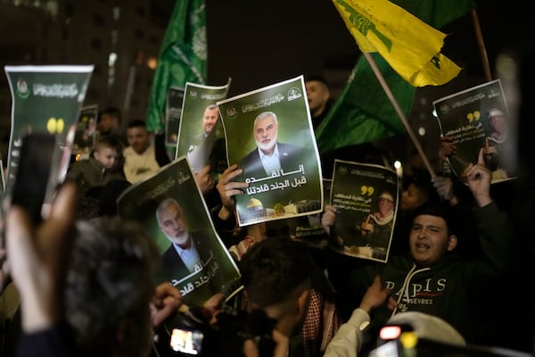 Palestinians hold posters with the photo of late Hamas leader Ismail Haniyeh as they wait for the arrival of the released Palestinian prisoners, in the West Bank city of Beitunia, on Sunday, Jan. 19, 2025. (AP Photo/Leo Correa)