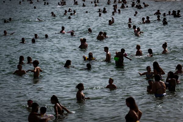 FILE - People cool off on a beach in Barcelona, Spain, July 12, 2023. (AP Photo/Emilio Morenatti, File)