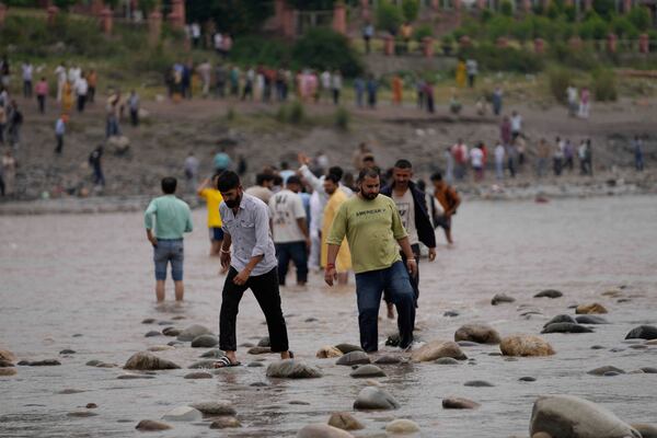 People cross the Chenab River after the flow of water was halted from a dam, at Akhnoor, on the outskirts of Jammu, India, Monday, May 5, 2025. (AP Photo/Channi Anand)