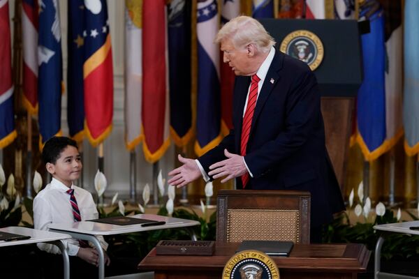 President Donald Trump, right, looking over to a young person during an education event and executive order signing in the East Room of the White House in Washington, Thursday, March 20, 2025. (AP Photo/Jose Luis Magana)