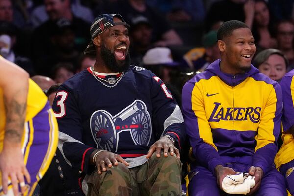 Los Angeles Lakers' LeBron James, left, laughs as he sits on the bench during the first half of an NBA basketball game against the Denver Nuggets Wednesday, March 19, 2025, in Los Angeles. (AP Photo/Mark J. Terrill)