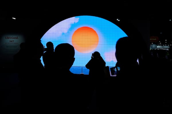 People watch a video displayed on a screen at a LG Electronics booth during the CES tech show Tuesday, Jan. 7, 2025, in Las Vegas. (AP Photo/Abbie Parr)