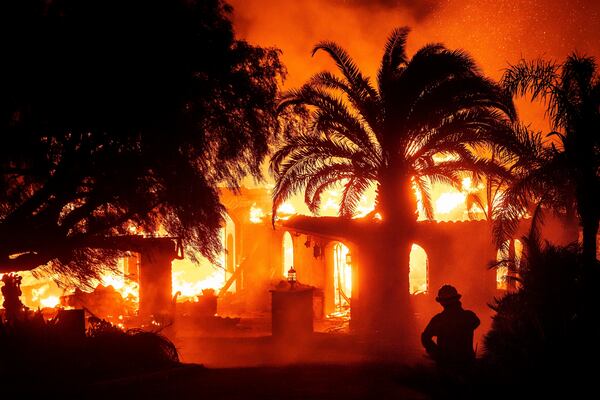 FILE - A firefighter watches as flames from the Mountain Fire consume a home in Camarillo, Calif., Nov. 6, 2024. (AP Photo/Noah Berger, File)