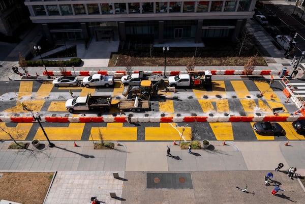 A man in a U.S.A.-themed blazer and red pants takes a cell phone photo at bottom right, as demolition begins on the Black Lives Matter mural, seen from above, Monday, March 10, 2025, in Washington. (AP Photo/Jacquelyn Martin)