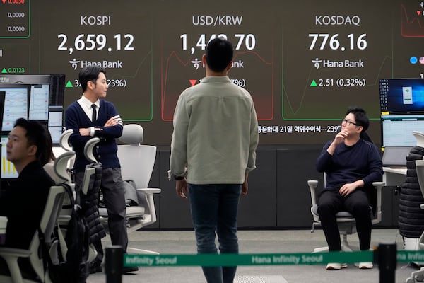 Currency traders work near a screen showing the Korea Composite Stock Price Index (KOSPI), top left, and the foreign exchange rate between U.S. dollar and South Korean won, top center, at the foreign exchange dealing room of the KEB Hana Bank headquarters in Seoul, South Korea, Wednesday, Feb. 19, 2025. (AP Photo/Ahn Young-joon)