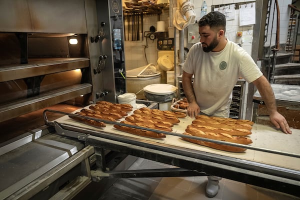 An employee removes bread for the oven in a bakery in Paris, Monday, Dec. 16, 2024 as butter has shot up in price across Europe in recent months, adding more pain to consumers this holiday season after years of inflation in the wake of the COVID-19 pandemic and war in Ukraine.(AP Photo/Aurelien Morissard)