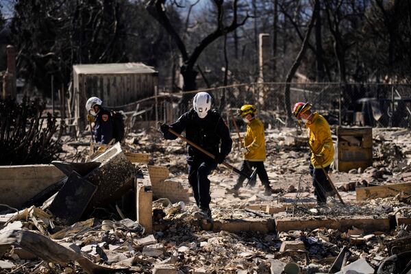 A search and rescue crew sifts through the wreckage of a home destroyed by the Eaton Fire, Tuesday, Jan. 14, 2025, in Altadena, Calif. (AP Photo/John Locher)