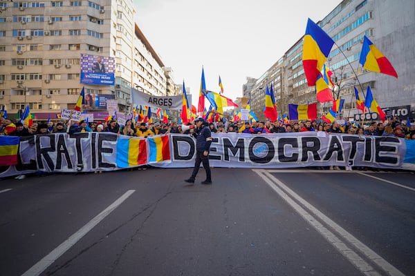 Protesters walk holding Romanian flags during a rally organized by the right wing Alliance for the Unity of Romanians (AUR), calling for free elections after Romania' s Constitutional Court annulled the first round of presidential elections last December, in Bucharest, Romania, Sunday, Jan. 12, 2025.(AP Photo/Vadim Ghirda)