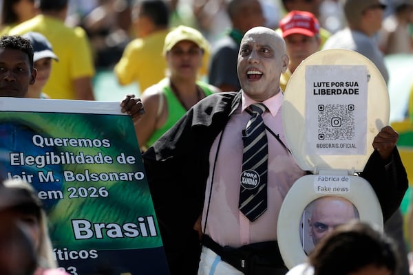 A supporter of former President Jair Bolsonaro, dressed as Supreme Court Justice Alexandre de Moraes, takes part in a rally on Copacabana Beach in support of a proposed bill to grant amnesty to those arrested for storming government buildings in an alleged coup attempt in 2023, in Rio de Janeiro, Sunday, March 16, 2025. (AP Photo/Bruna Prado)