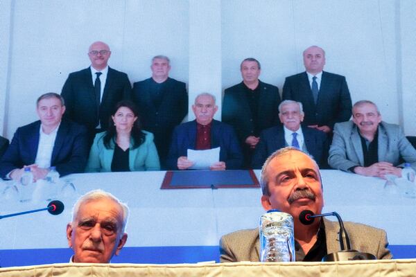 Pro-Kurdish Peoples' Equality and Democracy Party, or DEM, delegation members release an statement from the jailed leader of the rebel Kurdistan Workers' Party, or PKK, Abdullah Ocalan, center at the background photo, in Istanbul, Turkey, Thursday, Feb. 27, 2025. (AP Photo/Khalil Hamra)